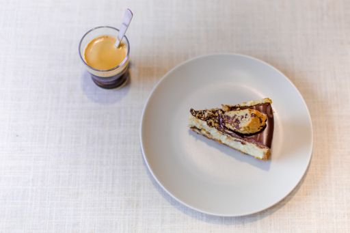A high angle shot of a coffee glass near a tasty looking cake piece