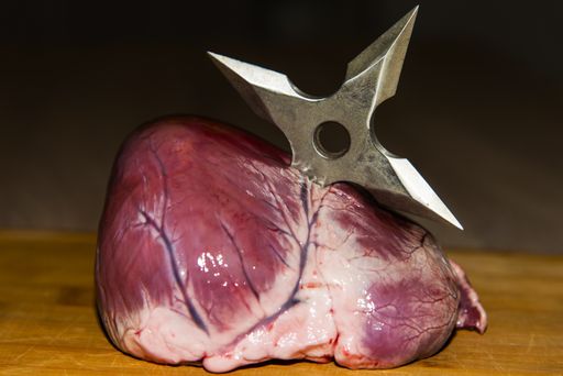 a shuriken plunged into an artificial heart on a wooden table