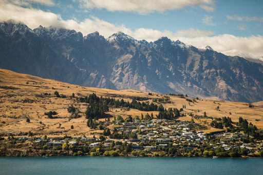 A beautiful scenery of a landscape with a lot of buildings near high rocky mountains by the sea