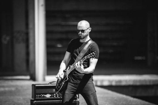 A grayscale shot of a male musician playing guit on a rock concert