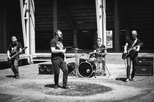 A grayscale shot of young musicians at an outdoor rock concert
