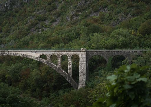 A low-angle view of a stone bridge in the forest in Italy