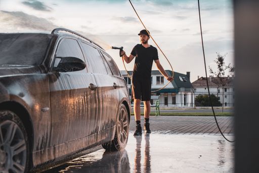 A man washing his car. A young boy taking care of his car.