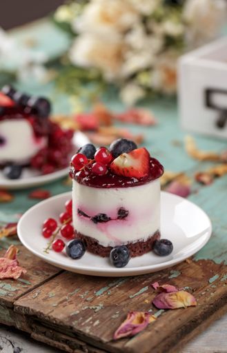 A vertical shot of mini fruit cakes on a white plate surrounded with berries