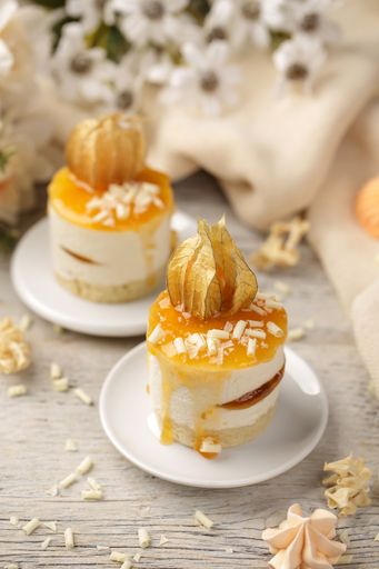 A vertical shot of mini peach cakes on a white plate surrounded by flowers