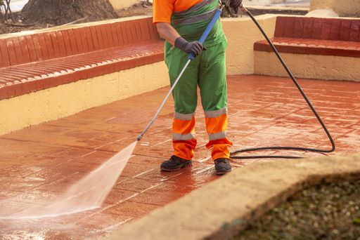 A worker cleaning the streets with a pressurized bleach water gun - the concept of coronavirus prevention