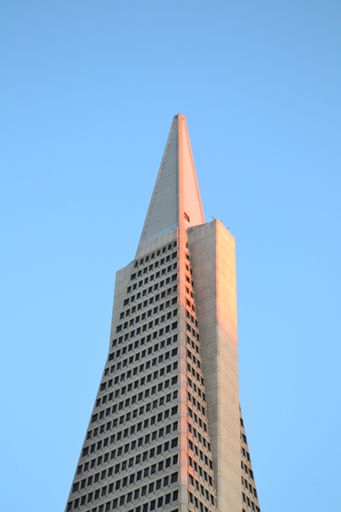 A low angle shot of the Transamerica tower under a blue sky during sunset
