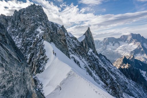 Climbers or alpinist on a knife sharp ridge of an alpine peak or summit of Aiguille du Rochefort. Alpine landscape and adventure climbing ascent.