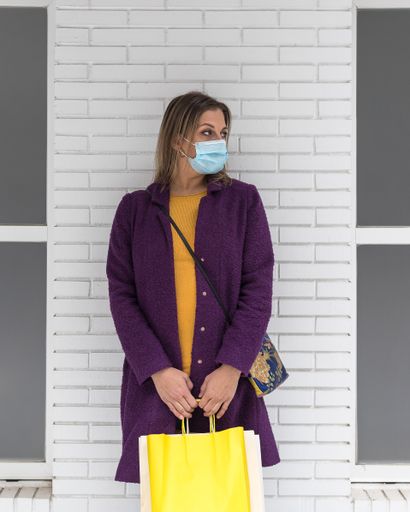 A vertical shot of a Caucasian blonde woman wearing a mask in a shopping mall