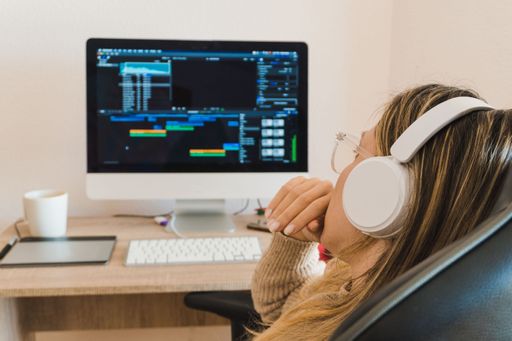 Blonde woman with headphones working on the computer at home, editing a video