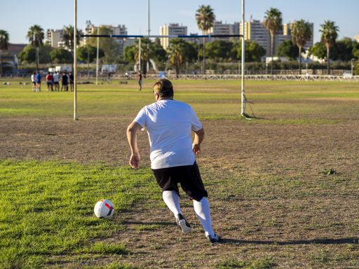 A football player with a white shirt kicking a ball from a penalty spot