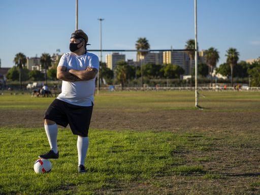 A football player with a white shirt standing on a football field and posing for the camera