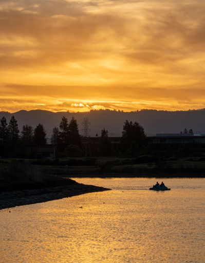 A dramatic shot of people on a paddle boat (pedalo) on the lake at sunset