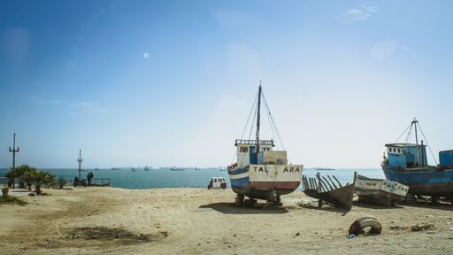 A fishing boat parked in the sand on a Talara beach during a sunny day