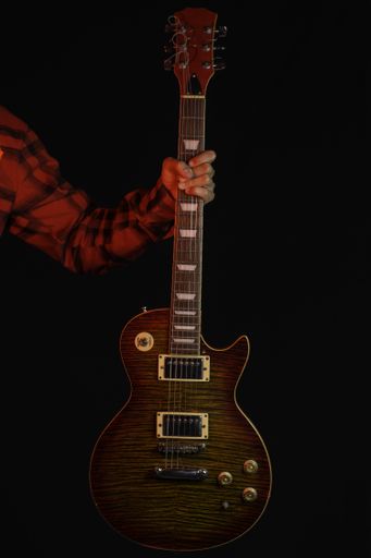 A closeup vertical shot of a man's arm holding an electric guitar neck