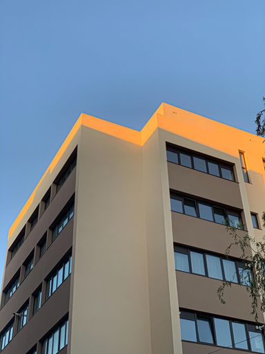 A vertical low angle shot of a residential building covered by the sunlight