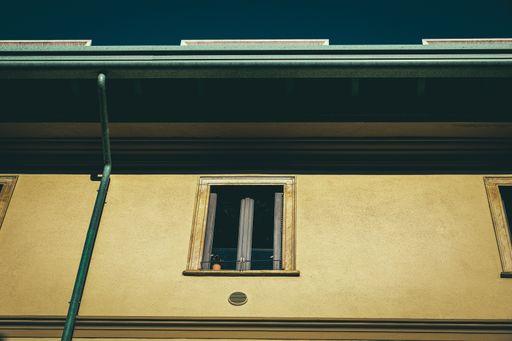 A low angle shot of a residential building window with a flower pot