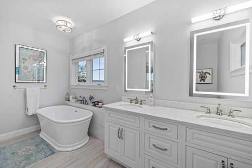 A light modern bathroom with two sinks, mirrors, and a small bath