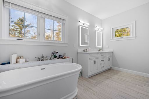 A light modern bathroom with two sinks, mirrors, and a bath