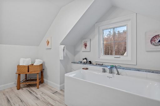 A light modern bathroom with a large bath against a small window