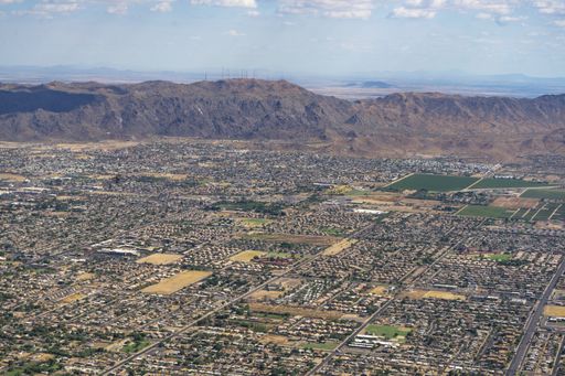 A high angle shot of a town with fields surrounded by high hills under a blue sky
