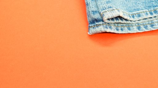A high angle shot of a pair of jeans on an orange surface