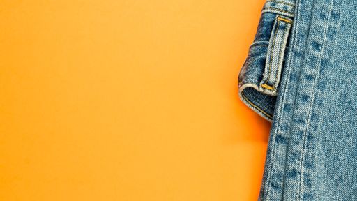 A high angle shot of a pair of jeans on an orange surface