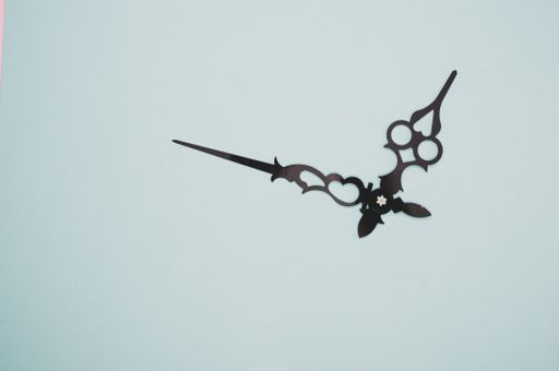 A high angle shot of a pair of clock hands on a blue surface