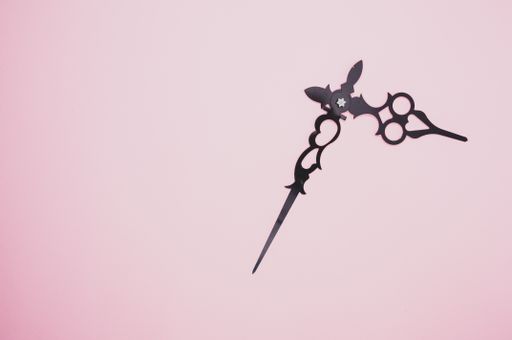 A high angle shot of a pair of clock hands on a purple surface