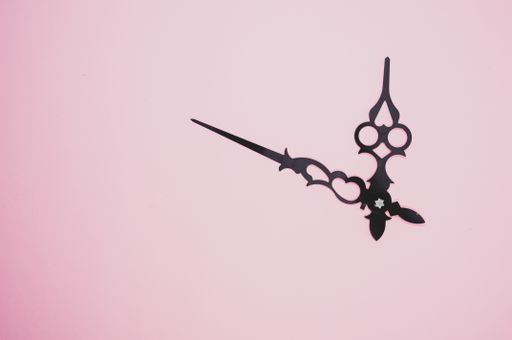A high angle shot of a pair of clock hands on a purple surface