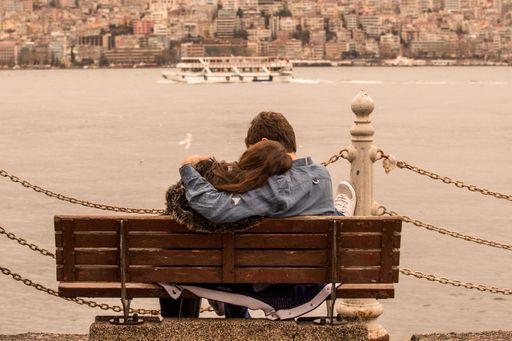 A lovely couple embracing and sitting on a bench near the river in Uskudar, Turkey