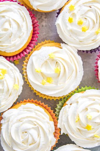 Tasty looking cupcakes of different colors with white cream glazed over