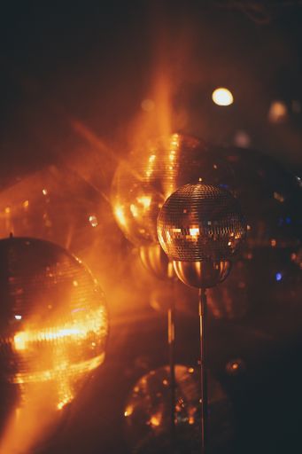 A closeup of mini disco balls under red and orange lights with a blurry background