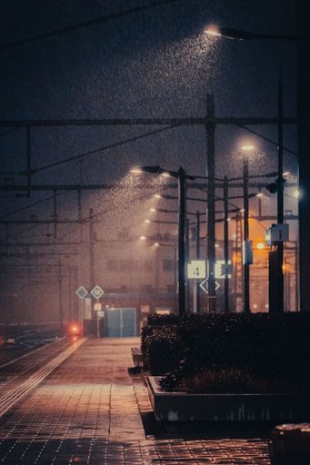A vertical shot of the illuminated empty street at night in the rain.