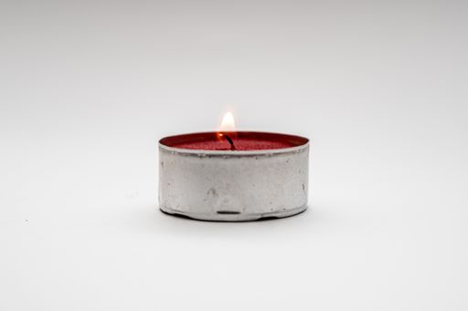 A small decorative red candles in metal case isolated on a white background