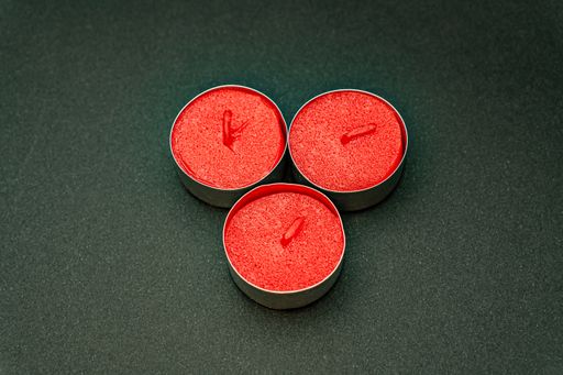 A closeup shot of small decorative red candles in metal cases isolated on a black background