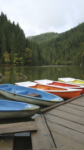 A vertical shot of the famous Red Lake with colorful boats near the dock in Lack Rosu, Romania
