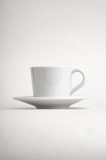 A vertical shot of a white little cup and saucer isolated on a white background