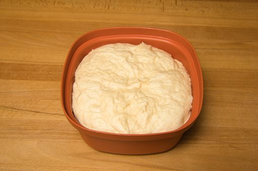 fresh risen yeast dough in a red bowl on a wooden table background, Germany