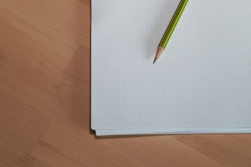 A paper sheet with a pencil on wooden table.