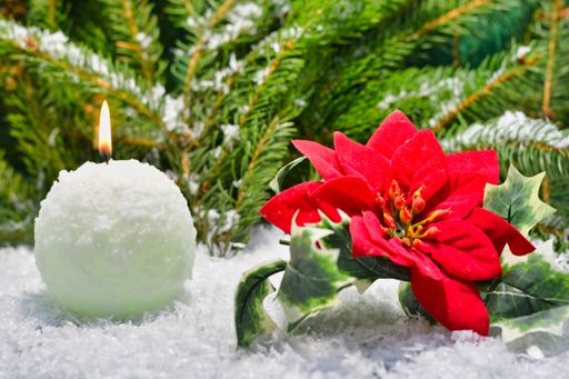 A closeup of a decorative Christmas snowball shaped burning candle