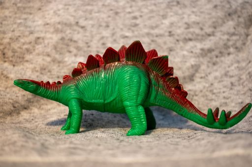 A closeup of a toy figurine of a green Stegosaurus dinosaur