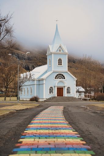 A vertical shot of colorful tiles leading to the Seydisfjordur Church in Iceland on a foggy day