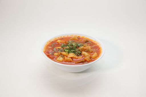 A high angle shot of  soup in a white bowl on a white background