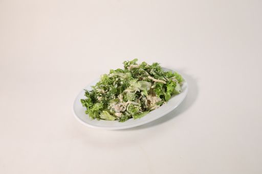 A high angle shot of a salad with chicken on a white plate on a white background
