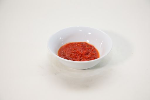 A high angle shot of ketchup in a white plate on a white background
