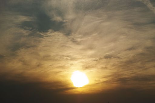 A mesmerizing shot of the sky during the sunset, the shining sun behind the clouds