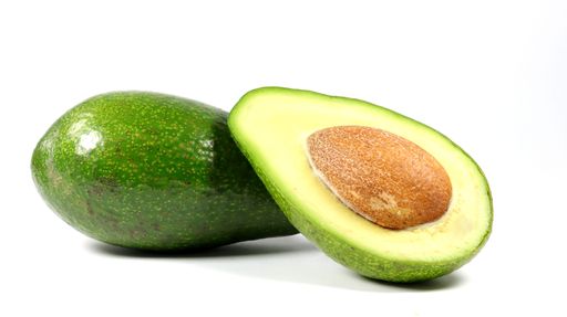 A closeup of an avocado with half of an avocado next to it, on a white background