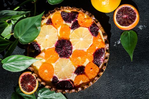 A high angle shot of a freshly baked delicious orange pie on a black surface