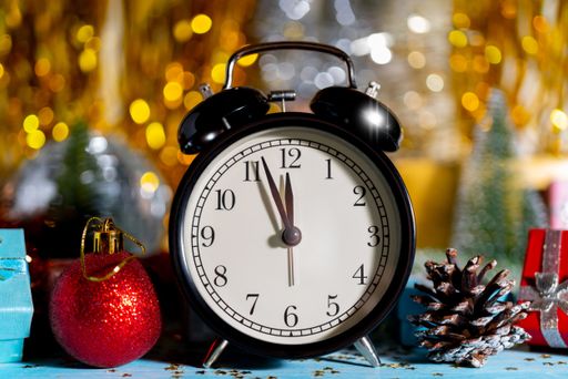 A Christmas composition on a shiny background, decorative toys and an alarm clock showing twelve o'clock